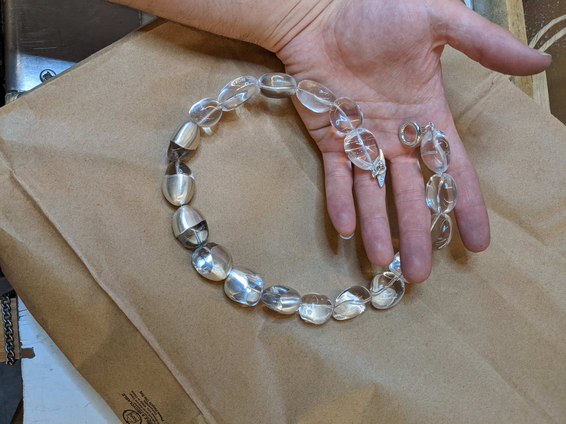 Quartz and sterling silver bead necklace laid out on kraft paper at the bench