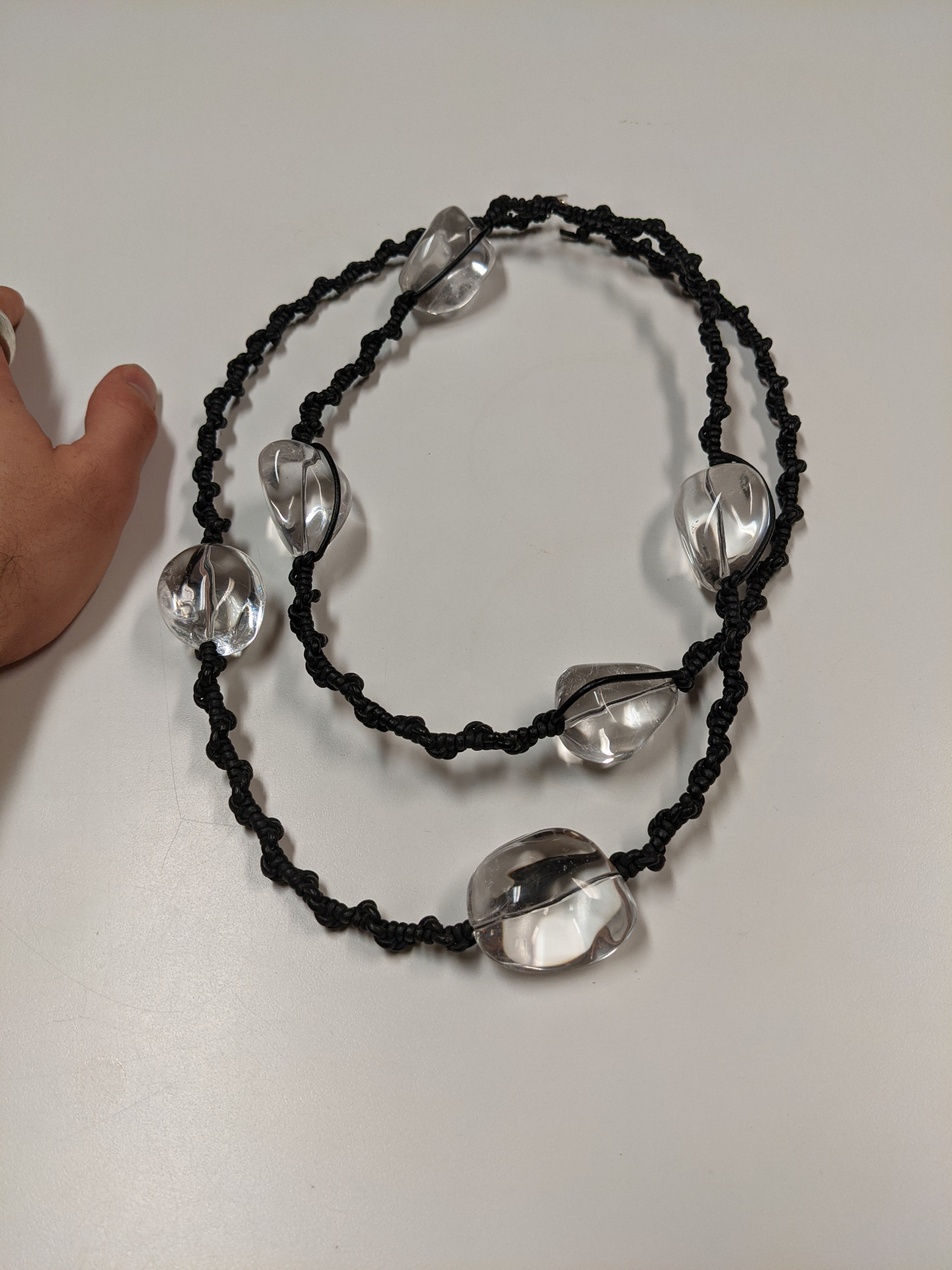 Minimal black cord bead necklace strung with large clear quartz forms on white background