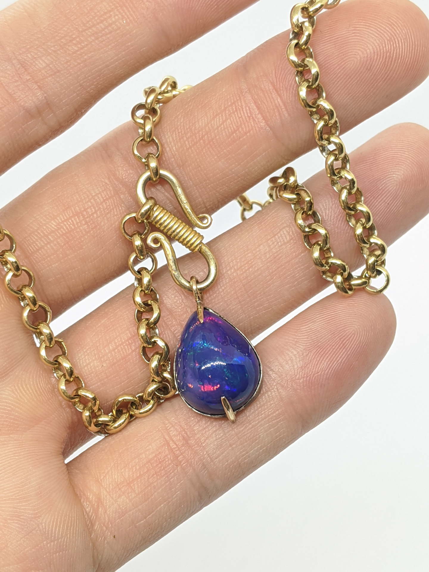 Early gold chain necklace with a pear-shaped opal pendant shown on hand