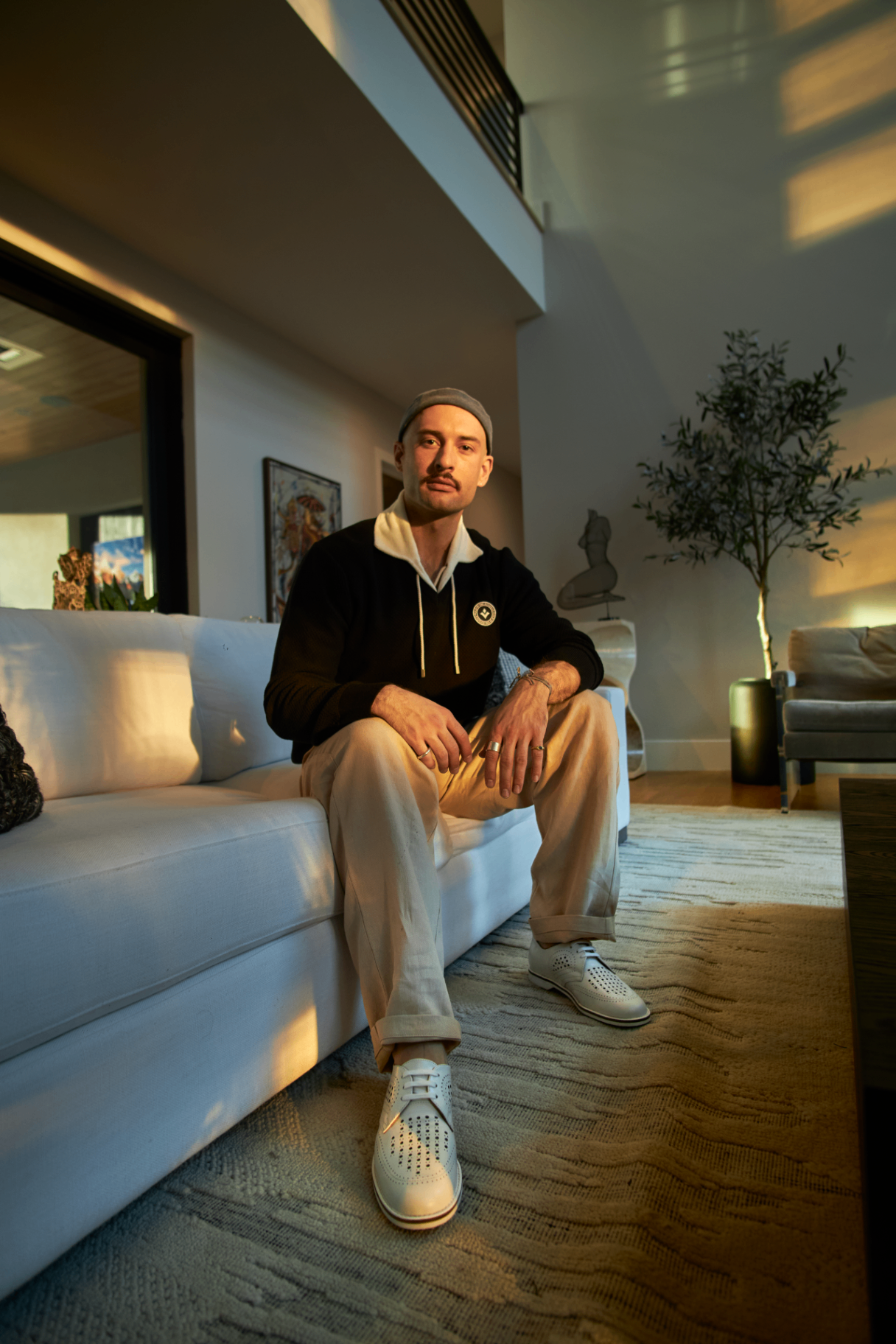 Studio portrait of Dayne seated on a sofa in warm afternoon light