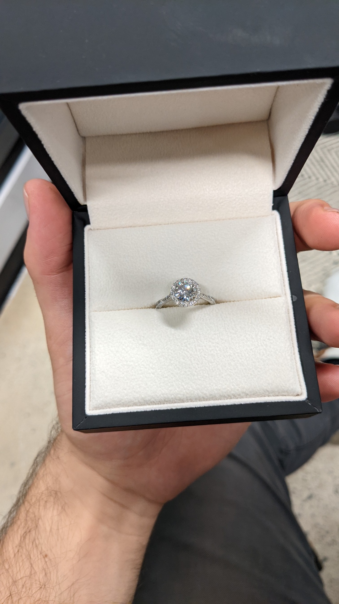 Round brilliant diamond halo engagement ring in a white velvet box
