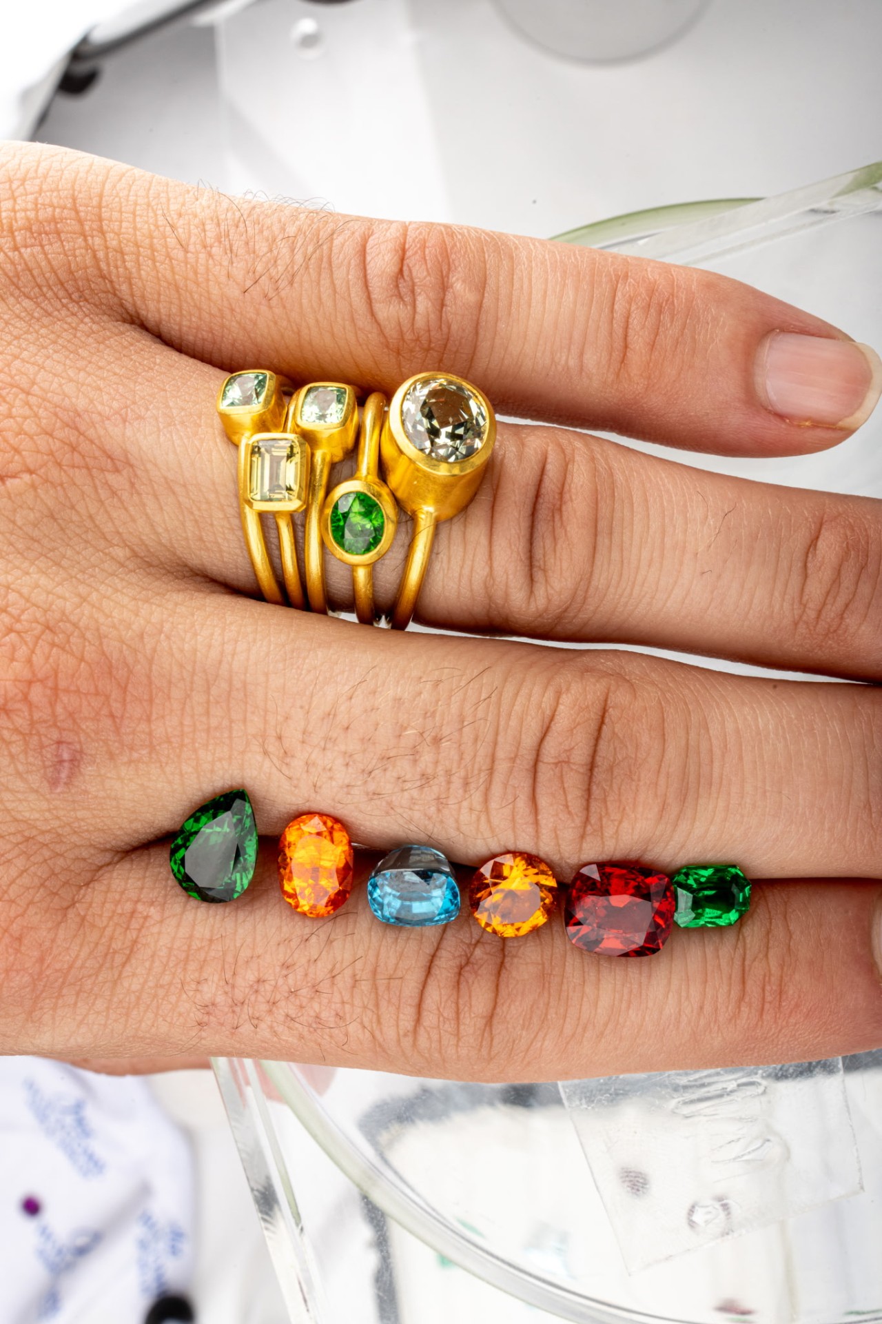 Gold ring stack alongside loose colored gemstones