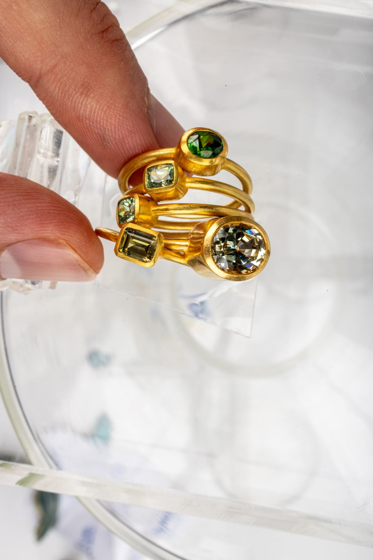 Stacked gold rings with green tourmaline and clear stones
