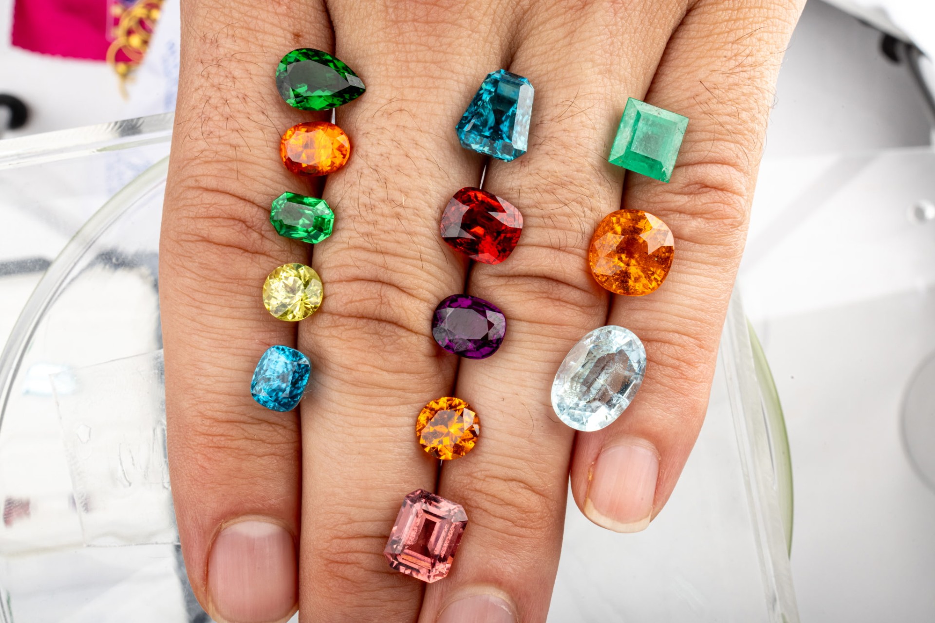 Collection of loose colored gemstones arranged on a hand