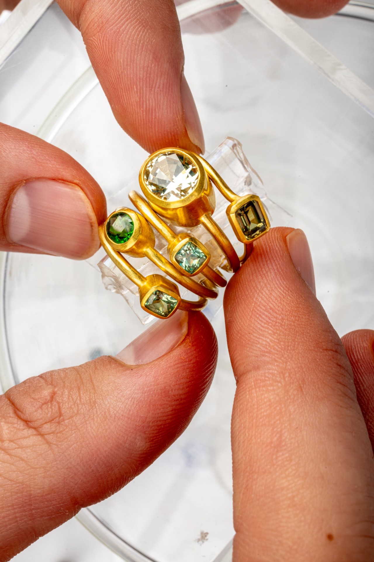 Five gold rings with assorted green and clear gemstones