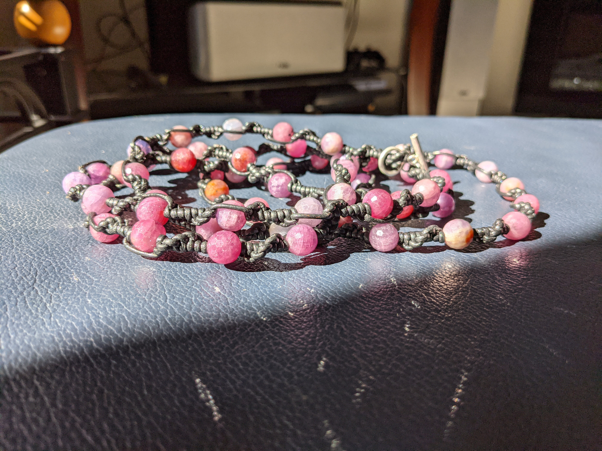 Close view of pink stone beadwork knotted into black cord with a silver clasp