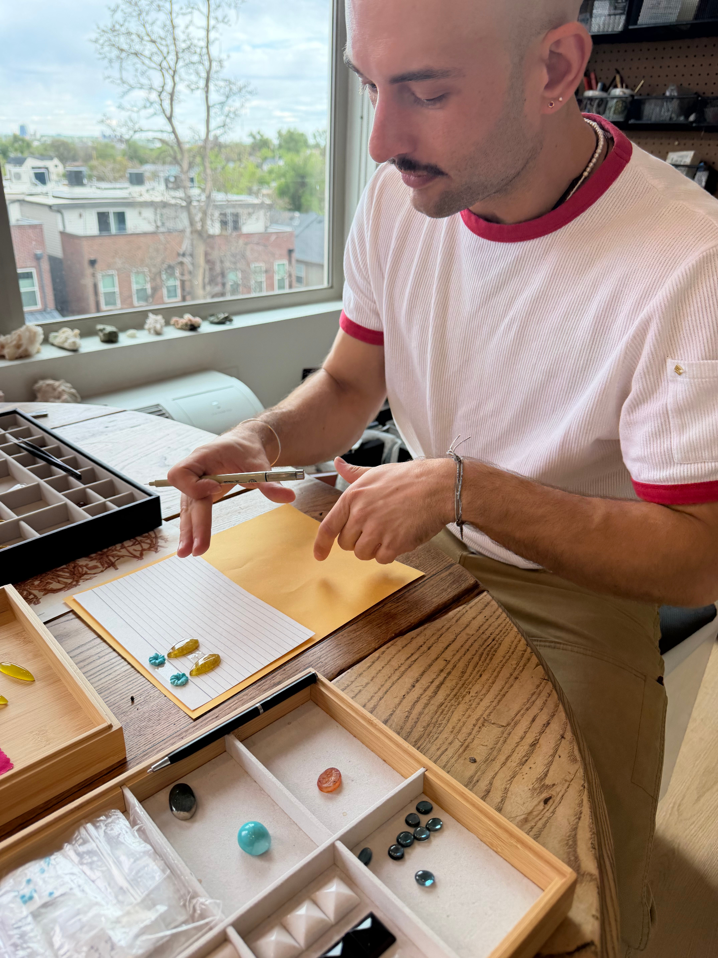 Dayne reviewing colorful gemstones at a work table by the window