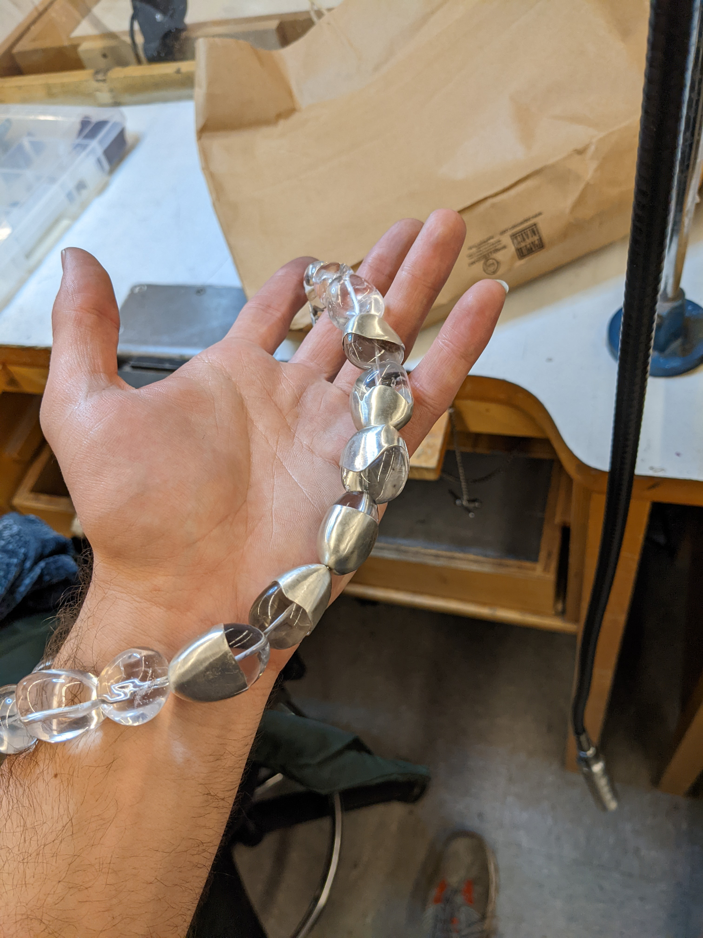 Quartz and silver bead necklace draped across the hand in the studio