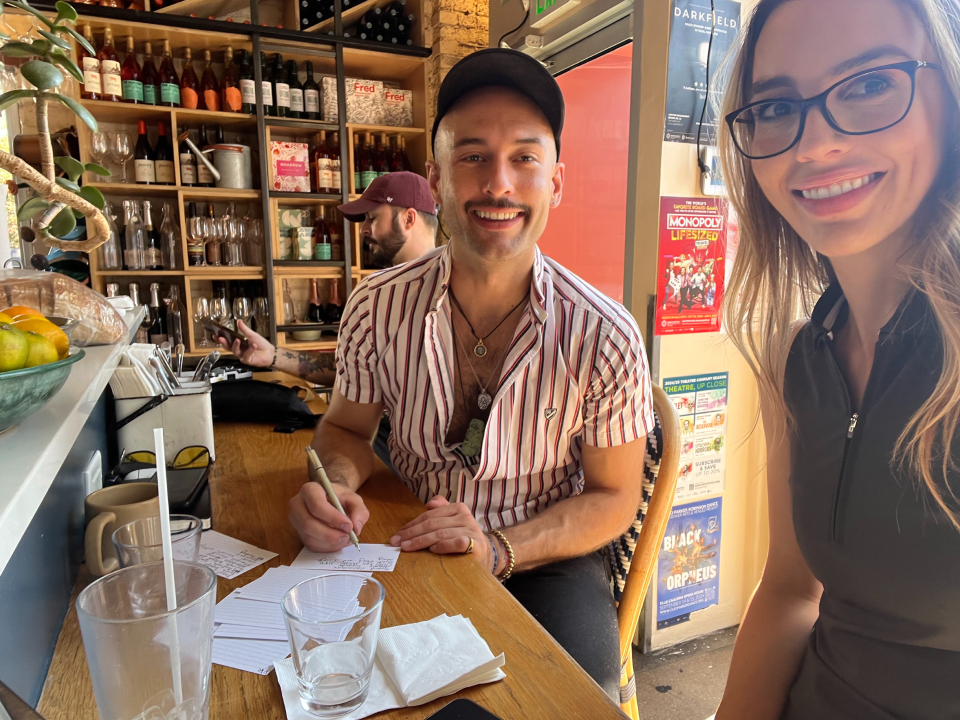 Dayne meeting with a client in a cafe while writing notes for a jewelry project