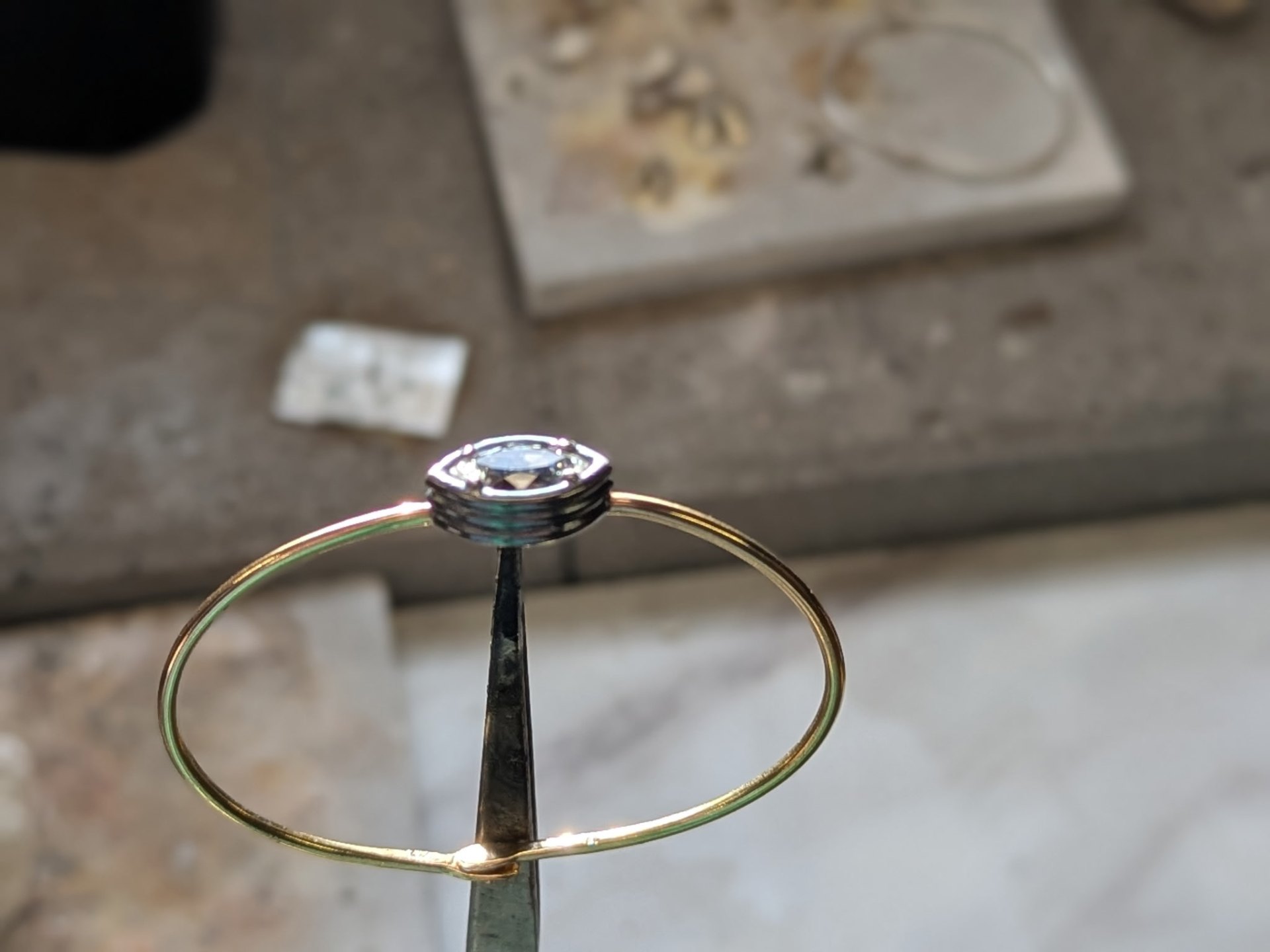 A rare gemstone and fine gold wire on a jeweler's work surface
